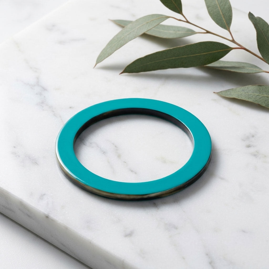 Branch Jewellery Turquoise Blue lacquered natural horn flat bangle with Turquoise Blue lacquer on both sides and black natural horn rim against a marble surface
