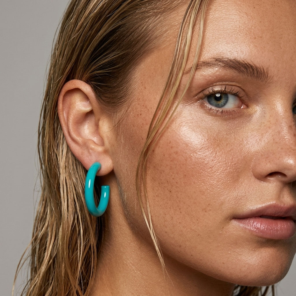 Close-up of a person wearing Branch Jewellery turquoise hoop earrings with a neutral background