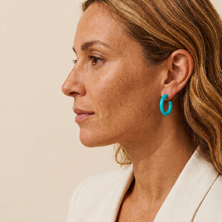 Branch Jewellery Rounded turquoise blue Lacquered horn hoop earrings, handcrafted with a glossy finish and featuring silver posts, are displayed against a white background.