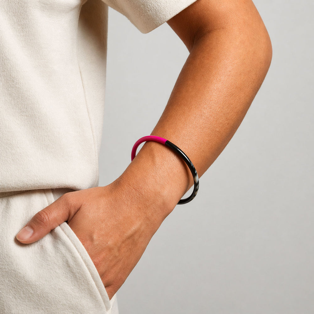 Branch Jewellery slim rounded black natural horn bangle with Fuchsia Pink Lacquer. Half of the bangle is natural black horn and half is covered in a smooth Fuchsia Pink lacquer.