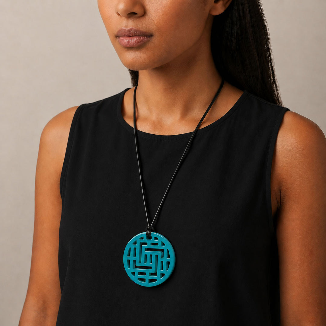 Woman wearing a black sleeveless top with a Branch Jewellery Moko Geometric Patterned Turquoise Blue Round cut-out Horn Pendant on black adjustable cord.