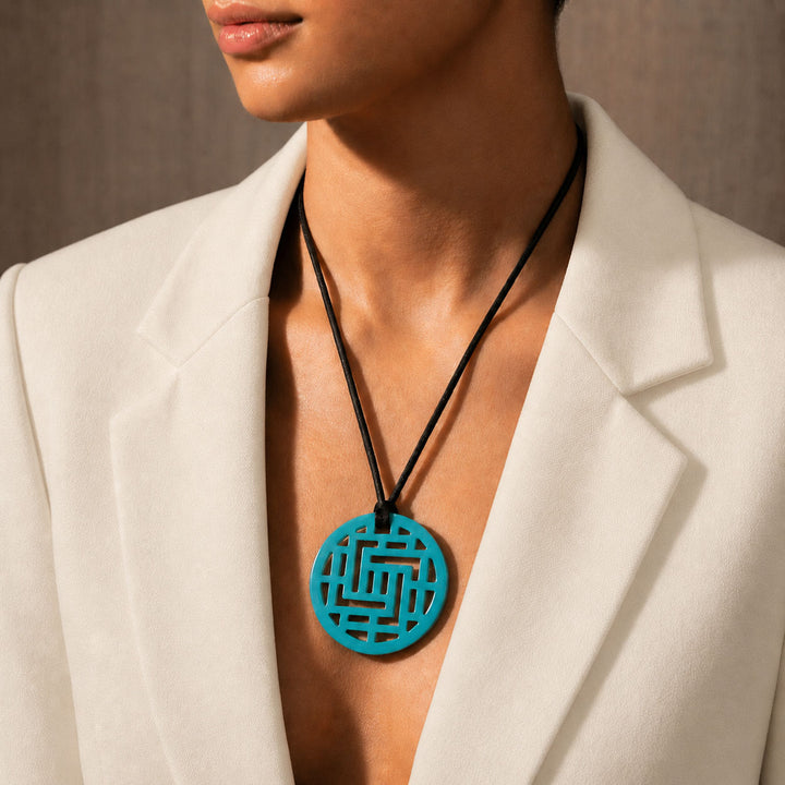 Person wearing a white blazer with a Branch Jewellery Moko Geometric Patterned Turquoise Blue Round cut-out Horn Pendant on black adjustable cord.