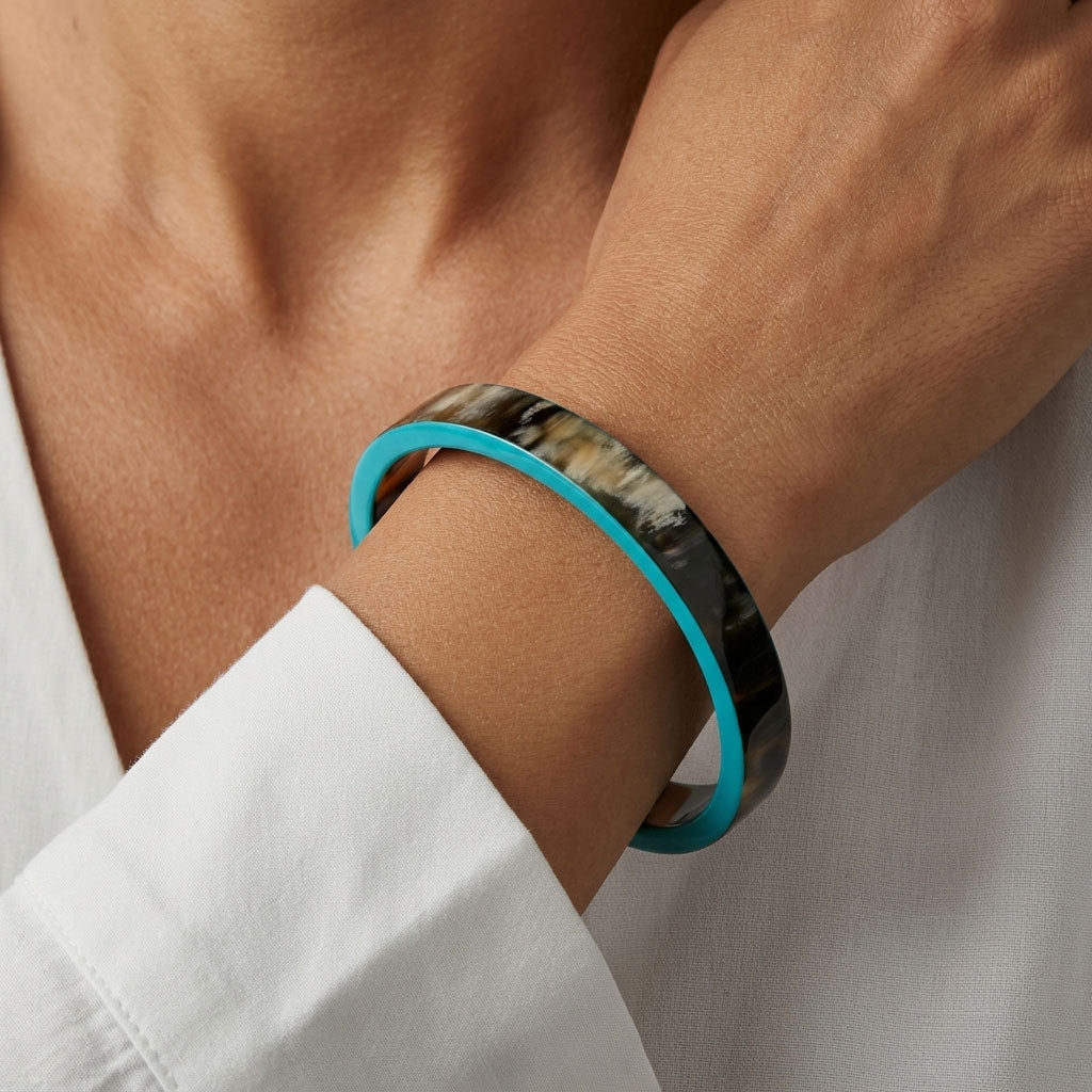 Close-up of a wrist wearing a Branch Jewellery Natural horn bangle with Turquoise Blue lacquered rim
