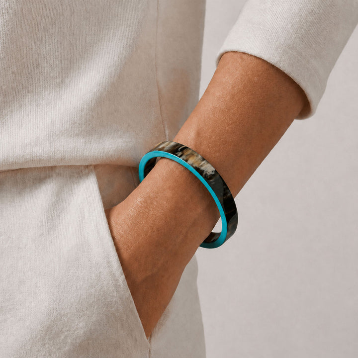 Person wearing aBranch Jewellery Natural horn bangle with Turquoise Blue lacquered rim on a neutral background