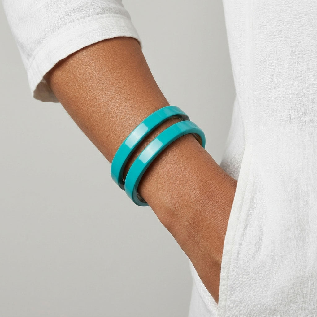 Person wearing a Branch Jewellery Turquoise Blue cut-out cuff lacquered buffalo horn bangle cuff on a wrist with a neutral background